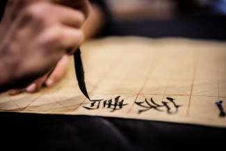 Close Up Photo Of A Hand Holding A Brush Writing Chinese Calligraphy