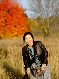 Photo Of Dr. Xiuyuan Mi Standing In A Field With Trees Behind Her