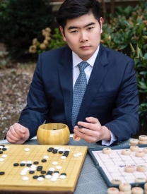 Headshot Of Haining Bao Sitting In Front Of Game Board
