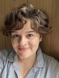Smiling white woman in her 30s with short wavy hair.