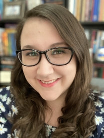 Headshot Of Theresa Tiliakos In Front Of A Bookshelf